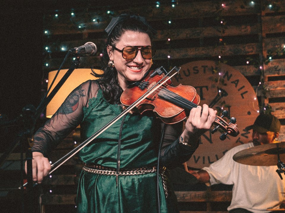 Tori smiling while playing fiddle at The Rusty Nail